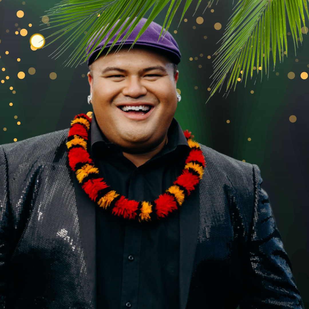 Jake Shimabukuro holds his ukulele and stands surrounded by a wreath of tropical flowers